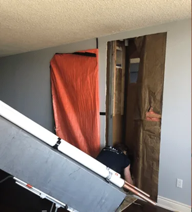 Opened riser shaft in a condominium suite with containment sheeting while BMI removes the old pipe